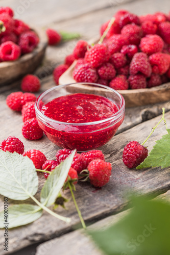 Jar of raspberry jam and fresh berries with leaves. Sweet dessert
