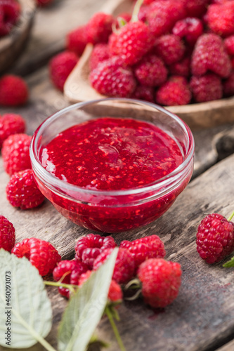 Jar of raspberry jam and fresh berries with leaves. Sweet dessert