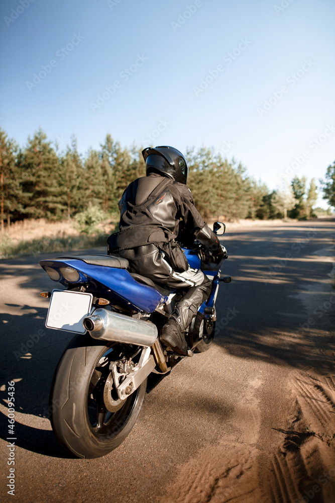 Fototapeta premium Beautiful motorcycle riding on a forest road. Have fun driving an empty road on a motorcycle ride in the warm sunbeams of the sunset.