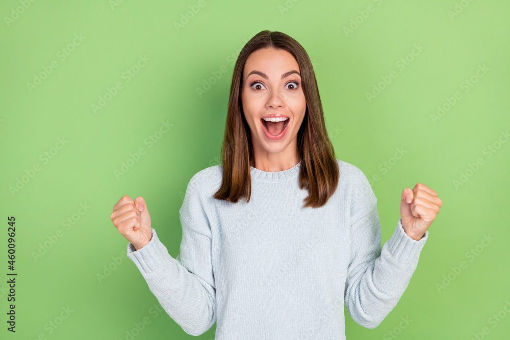 Photo of hooray millennial brunette lady hands fists wear blue jumper isolated on green color background Photo of hooray millennial brunette lady hands fists wear blue jumper isolated on green color background