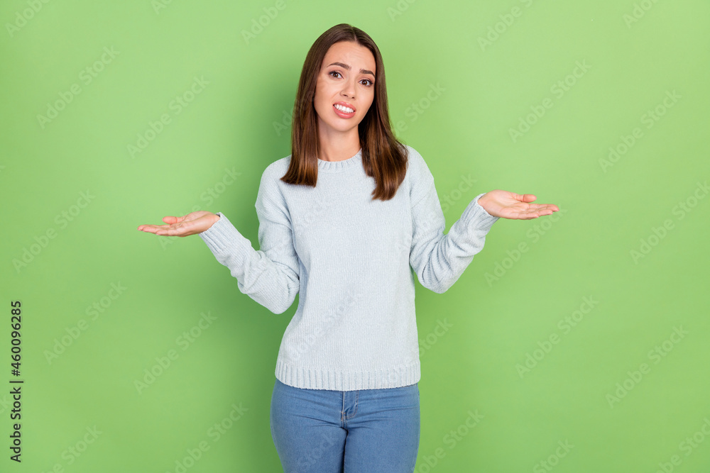 Photo of unhappy young brunette lady shrug shoulders wear blue jumper isolated on green color background Photo of unhappy young brunette lady shrug shoulders wear blue jumper isolated on green color background
