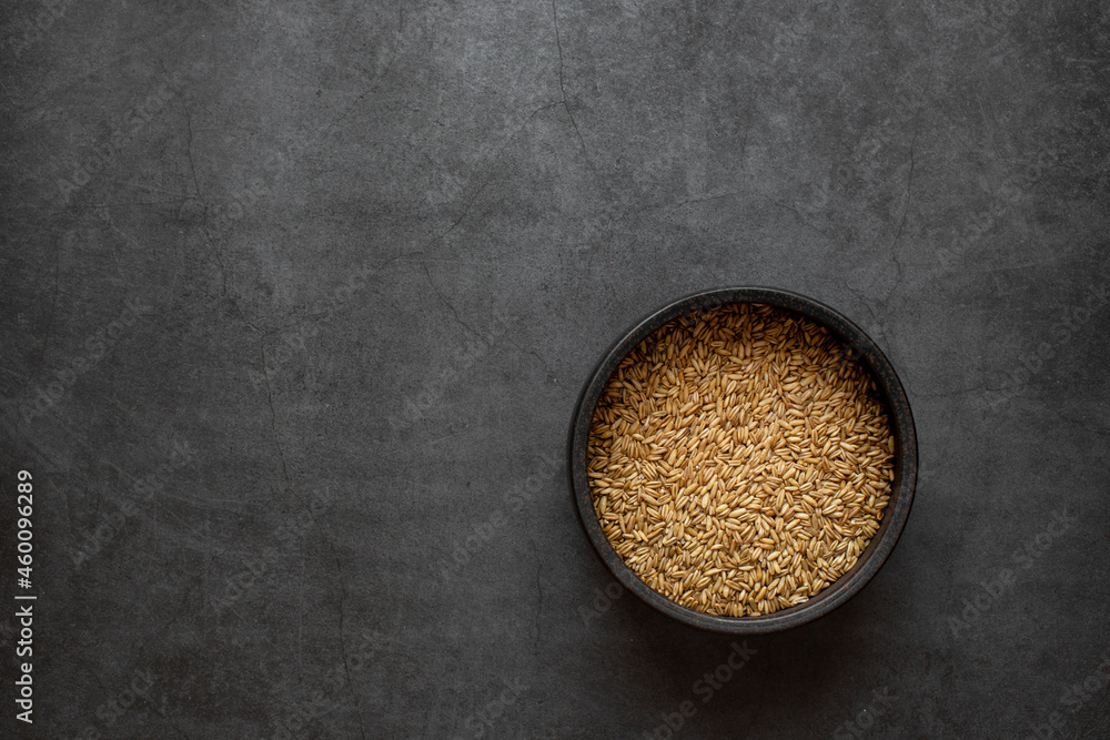 Oats rice in bowl on dark grey background. Oats rice in bowl on dark grey background.