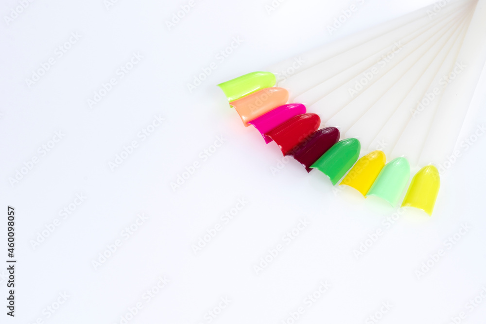 Fototapeta premium Multiсolor nail tips on a white background. examples of manicure for nails. Palette with color samples of nail. Copy space
