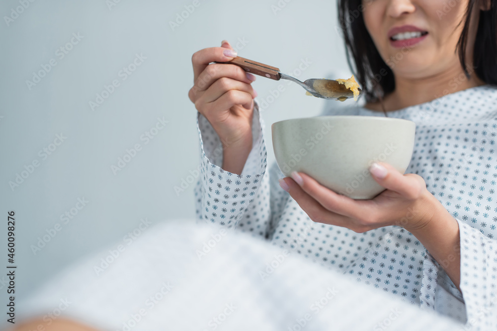 cropped view of disgusted woman holding spoon with corn flakes and bowl in hospital cropped view of disgusted woman holding spoon with corn flakes and bowl in hospital