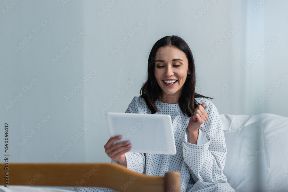 happy woman in patient gown using digital tablet in hospital happy woman in patient gown using digital tablet in hospital