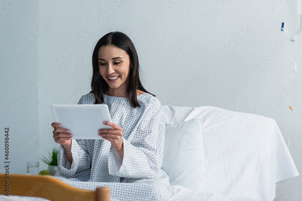 cheerful woman using digital tablet in hospital