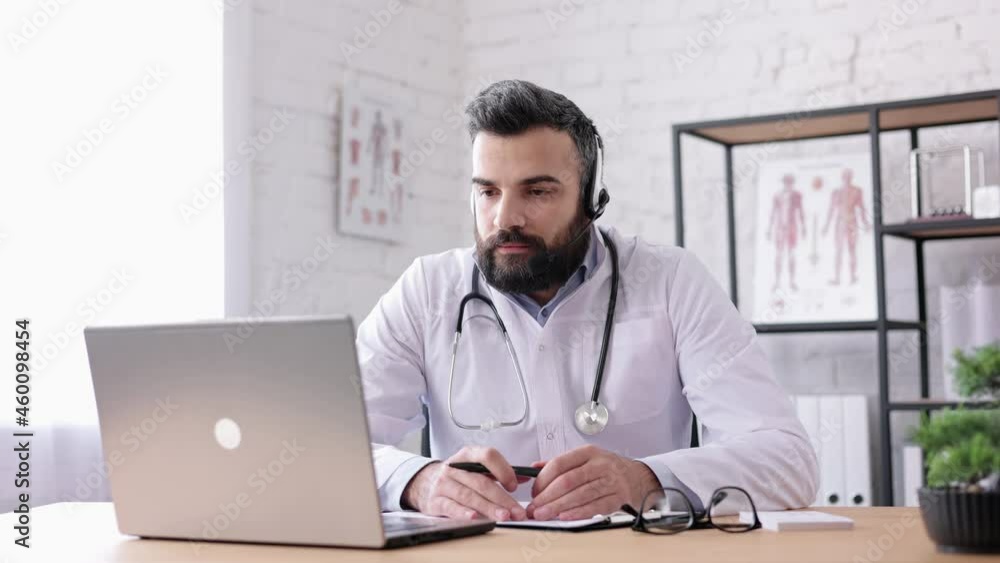 Male doctor wearing white coat consulting patient remote online using headset and web camera on laptop.Video call, video chat,conference with colleagues.Telemedicine.Remote healthcare services concept Male doctor wearing white coat consulting patient remote online using headset and web camera on laptop.Video call, video chat,conference with colleagues.Telemedicine.Remote healthcare services concept