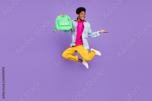 Photo of promoter guy jump hold rucksack hand empty space wear blue shirt isolated violet color background