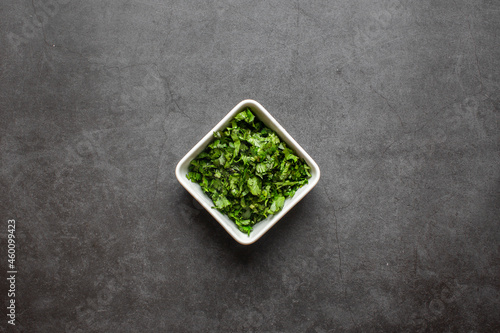 Chopped Fresh Coriander leaves in white plate on black background. top view. © litchima