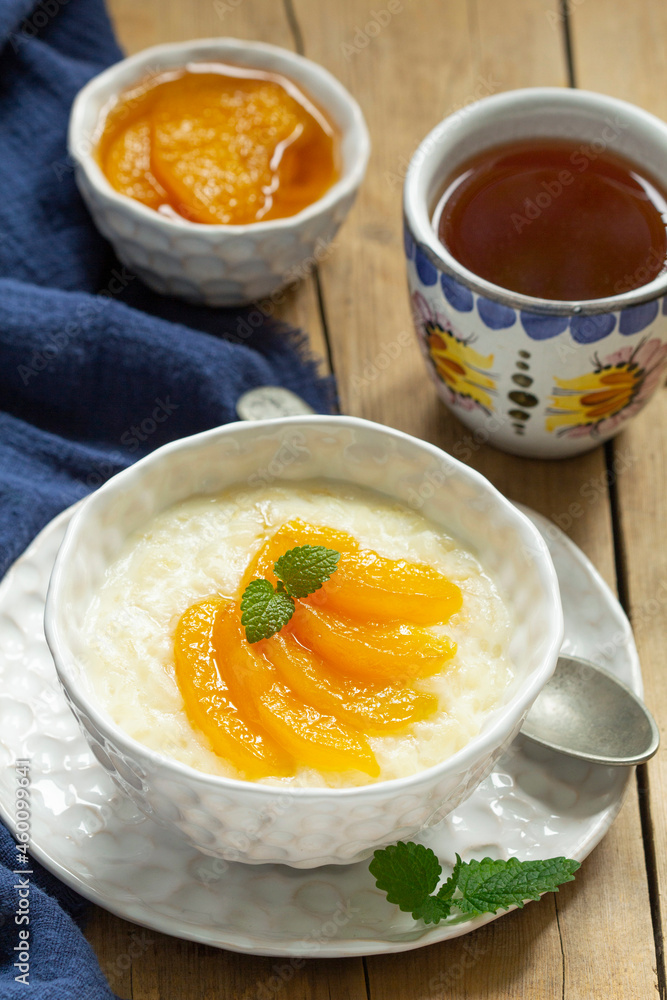Breakfast of rice porridge with peach jam and tea. Rustic style. Breakfast of rice porridge with peach jam and tea. Rustic style.