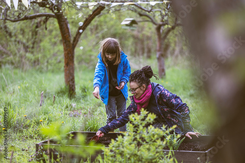 Mother and daughter planting seeds in the community garden
