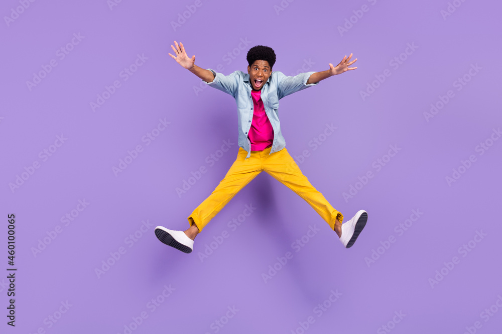 Photo of inspired crazy guy jump raise hands open mouth wear blue shirt pants shoes isolated purple color background