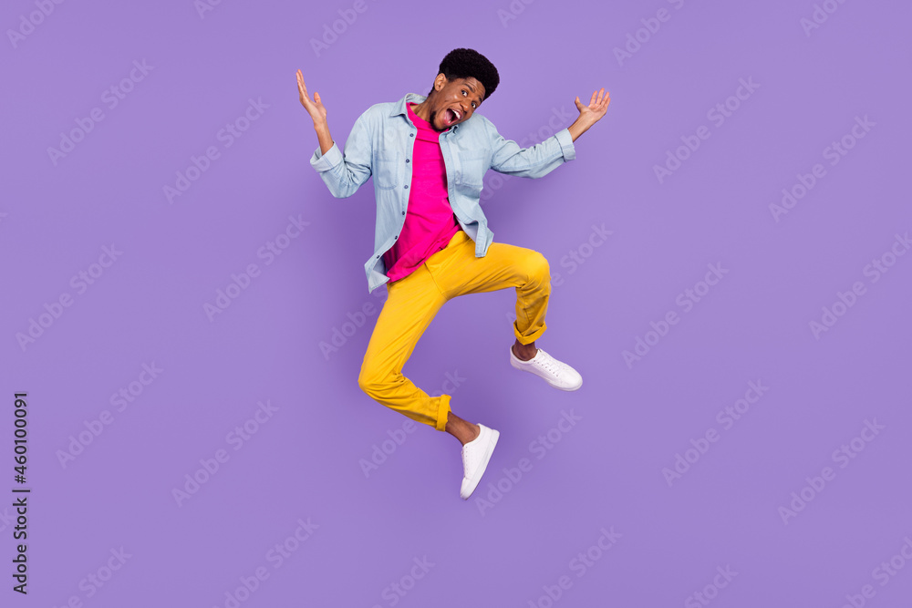 Photo of foolish clueless afro guy jump raise hands wear blue shirt pants footwear isolated violet color background
