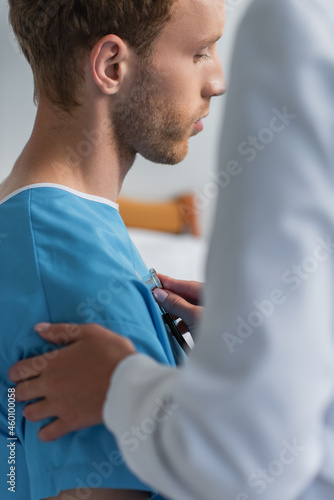 blurred doctor examining curly patient with stethoscope