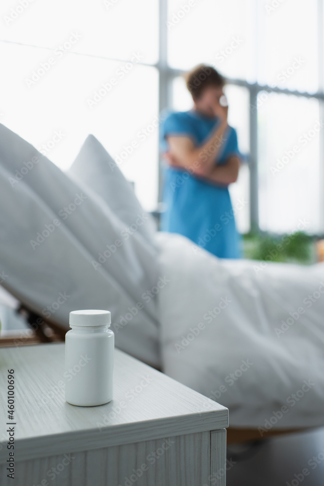 bottle with medication on bedside table near blurred patient in hospital bottle with medication on bedside table near blurred patient in hospital