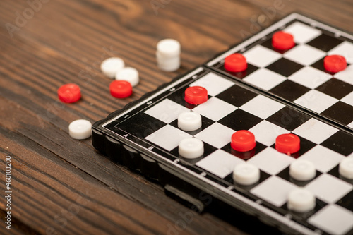 A board for playing checkers with chips on a wooden table, close-up, selective focus.