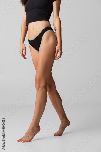 Cropped image of sportive female body in lingerie posing isolated on light gray studio background. Natural beauty concept.