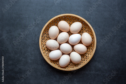 Fresh Chicken eggs in Bamboo basket on a dark gray background.