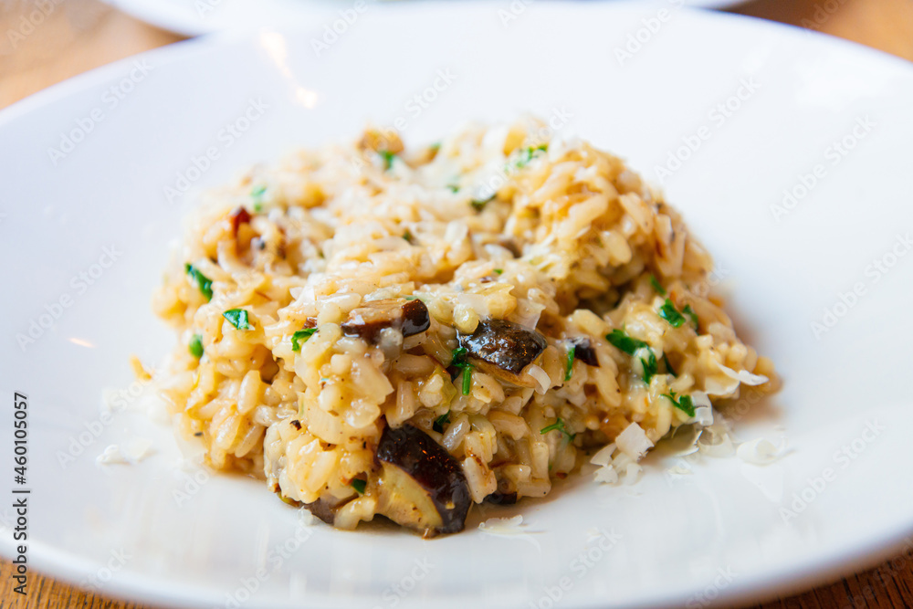 Delicious Italian vegetarian risotto cooked with mushrooms and onions served in white plate.