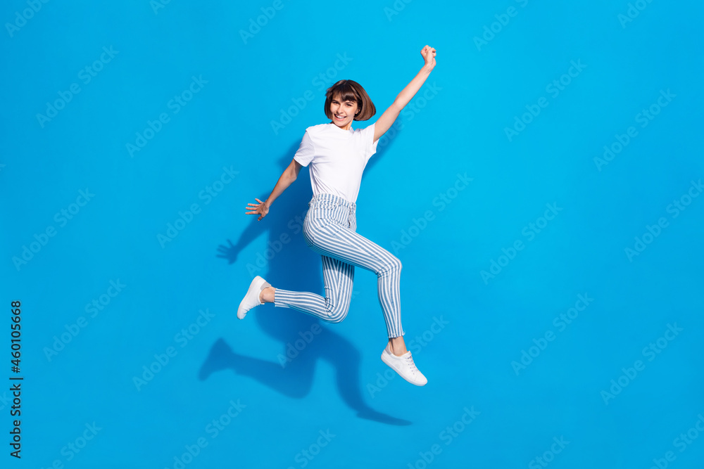 Photo of shiny pretty young woman dressed casual clothes running rising fists smiling isolated blue color background