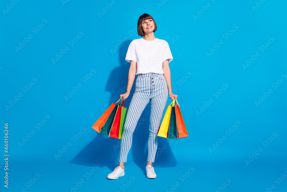 Full length body size photo girl keeping bags after sale looking copyspace isolated bright blue color background Full length body size photo girl keeping bags after sale looking copyspace isolated bright blue color background