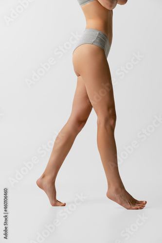 Cropped image of sportive female body in lingerie posing isolated on light gray studio background. Natural beauty concept.