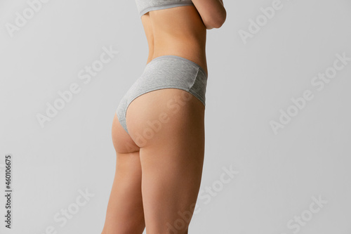 Back view of sportive body, bottocks of young woman in grey bottocks isolated on gray studio background. Natural beauty concept