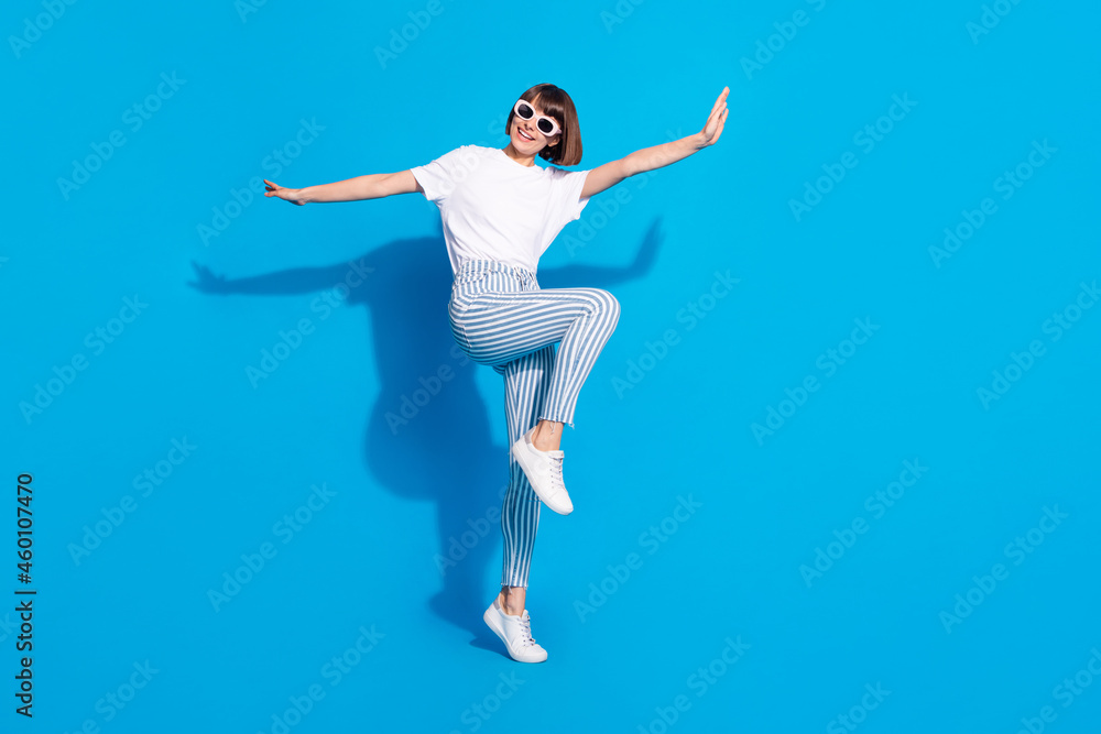 Photo of sweet funny young lady wear white outfit dark eyewear smiling dancing isolated blue color background