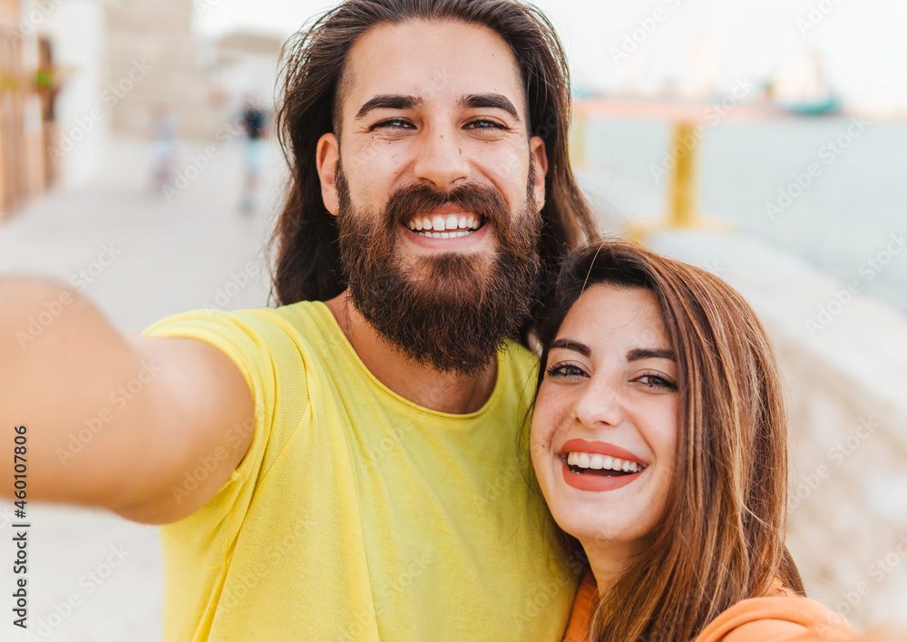 Happy couple on vacation take a funny selfie with smart phone looking at camera - lifestyle and sharing concept. Happy couple on vacation take a funny selfie with smart phone looking at camera - lifestyle and sharing concept.