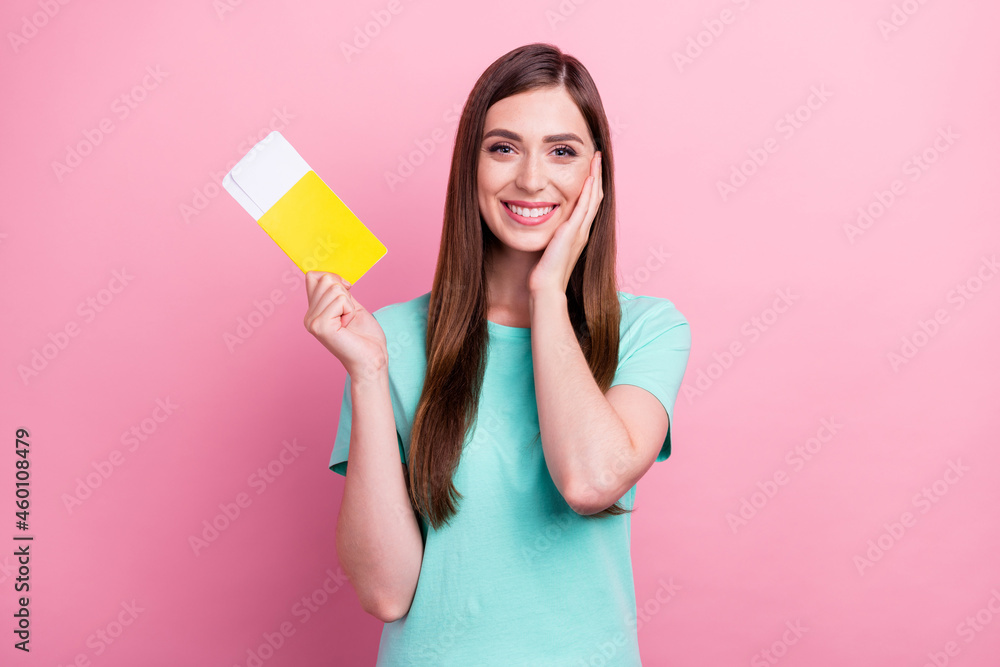 Photo of impressed excited young lady wear teal t-shirt smiling holding tickets arm cheek isolated pink color background Photo of impressed excited young lady wear teal t-shirt smiling holding tickets arm cheek isolated pink color background