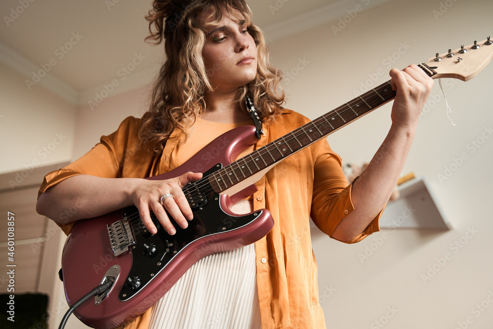 Obraz premium Female musician feeling involved while playing guitar at home at her room