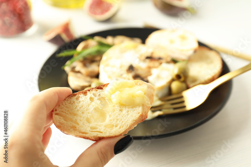 Female hand holds bread slice with camembert, close up and selective focus