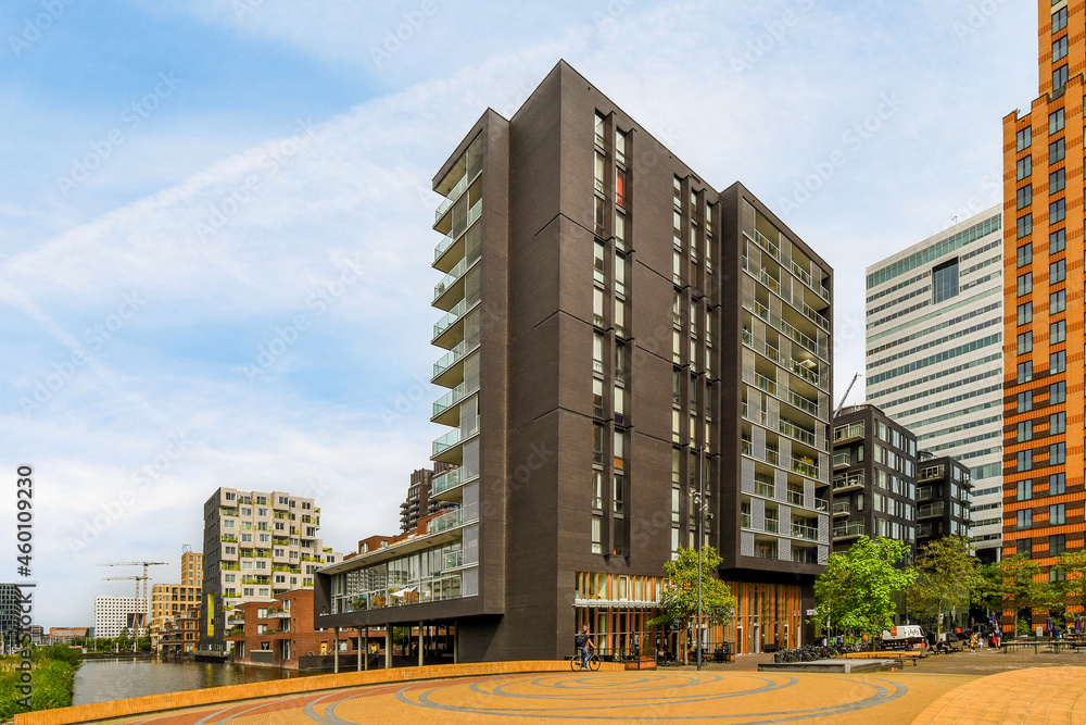 Contemporary multistory house facades against square and urban river Contemporary multistory house facades against square and urban river