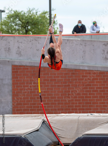 High School girls competing in pole vault at a track and field meet photo