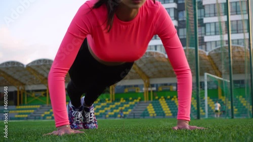 Fitness girl doing pushups exercise at workout on track. Sport woman doing push ups. Athletic woman training hard at stadium. Portrait of fit girl having outdoor workout.