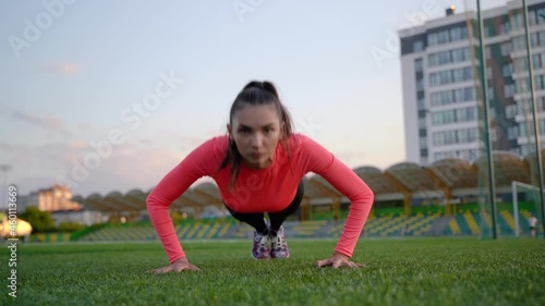 Fitness girl doing pushups exercise at workout on track. Sport woman doing push ups. Athletic woman training hard at stadium. Portrait of fit girl having outdoor workout.
