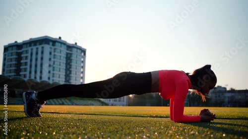 Fitness girl doing pushups exercise at workout on track. Sport woman doing push ups. Athletic woman training hard at stadium. Portrait of fit girl having outdoor workout.