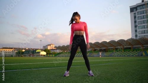 Fitness woman in sportswear doing various exercises on sports mat, on green football field with white markings, at stadium. Outdoor sports. online training. hot summer day. healthy lifestyle concept