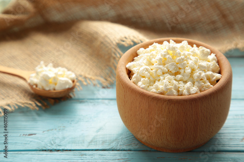 Cottage cheese for breakfast in wooden bowl on blue background.