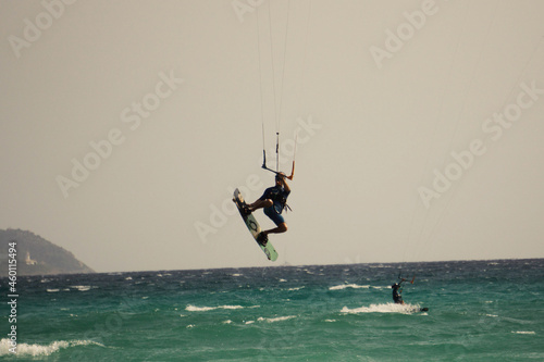Young male grabbing his board during a jump in kitesurfing