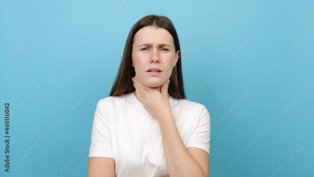 Unhealthy young woman touch neck hard to swallow having discomfort or painful feeling, unwell sad girl suffering from angina, sore throat, experience loss of voice, isolated on blue background studio Unhealthy young woman touch neck hard to swallow having discomfort or painful feeling, unwell sad girl suffering from angina, sore throat, experience loss of voice, isolated on blue background studio