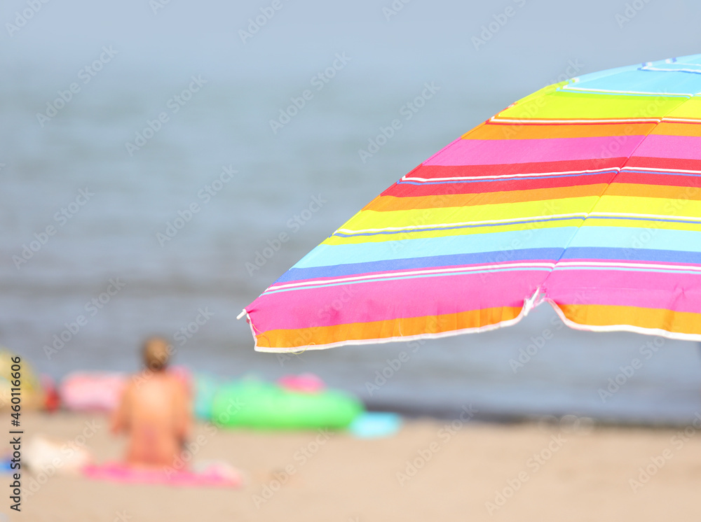 parasol umbrella on the beach with swimmers having fun during the summer holidays parasol umbrella on the beach with swimmers having fun during the summer holidays