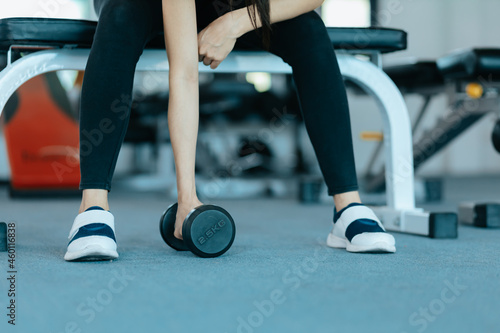 Fitness girl lifting dumbbell in fitness gym. Fitness workout and muscle concept.