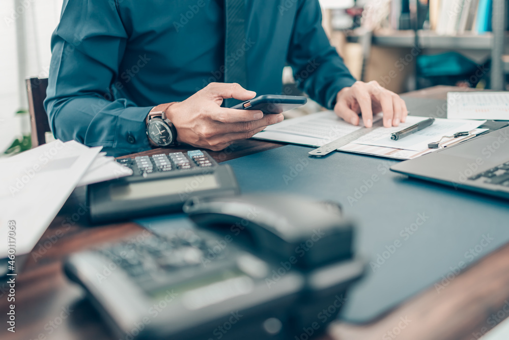 Fototapeta premium Businessman use cell phone and working on office desk and analyzing new project of accounting finance. Investment, Financial advisor and accounting concept.