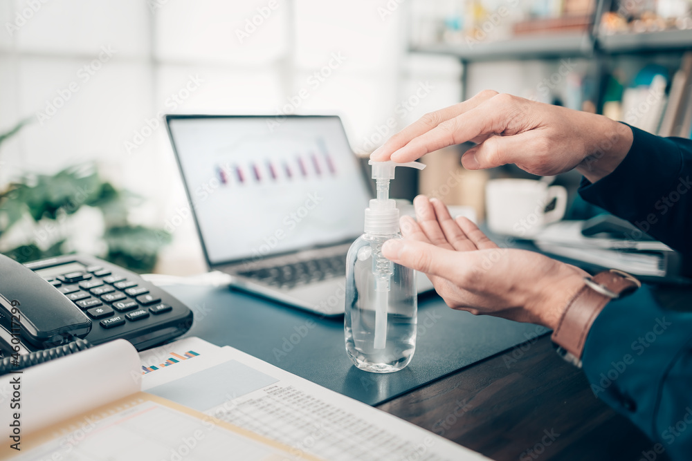 Man pressing hand sanitiser on his desk to wash his hands to prevent coronavirus. Clean hand concept. Man pressing hand sanitiser on his desk to wash his hands to prevent coronavirus. Clean hand concept.