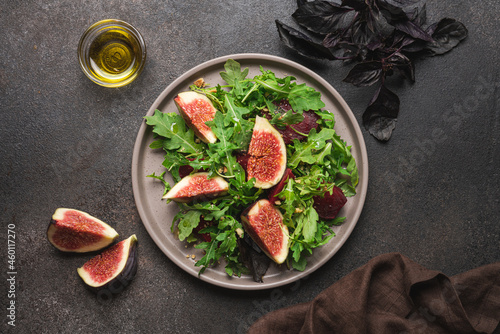 Figs, beetroot, arugula and walnuts salad. Black background, top view