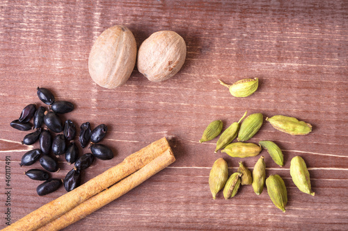 Cardamom, nutmeg, cinnamon and other aromatic spices lie on a wooden table