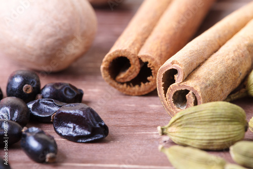 Cardamom, nutmeg, cinnamon and other aromatic spices lie on a wooden table