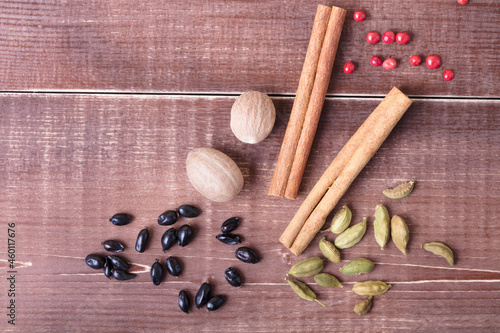 Cardamom, nutmeg, cinnamon and other aromatic spices lie on a wooden table