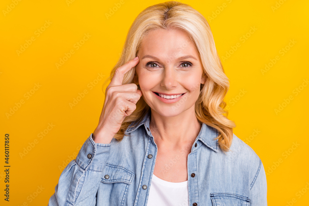 Photo of minded happy charming old woman finger head idea plan smile isolated on yellow color background Photo of minded happy charming old woman finger head idea plan smile isolated on yellow color background